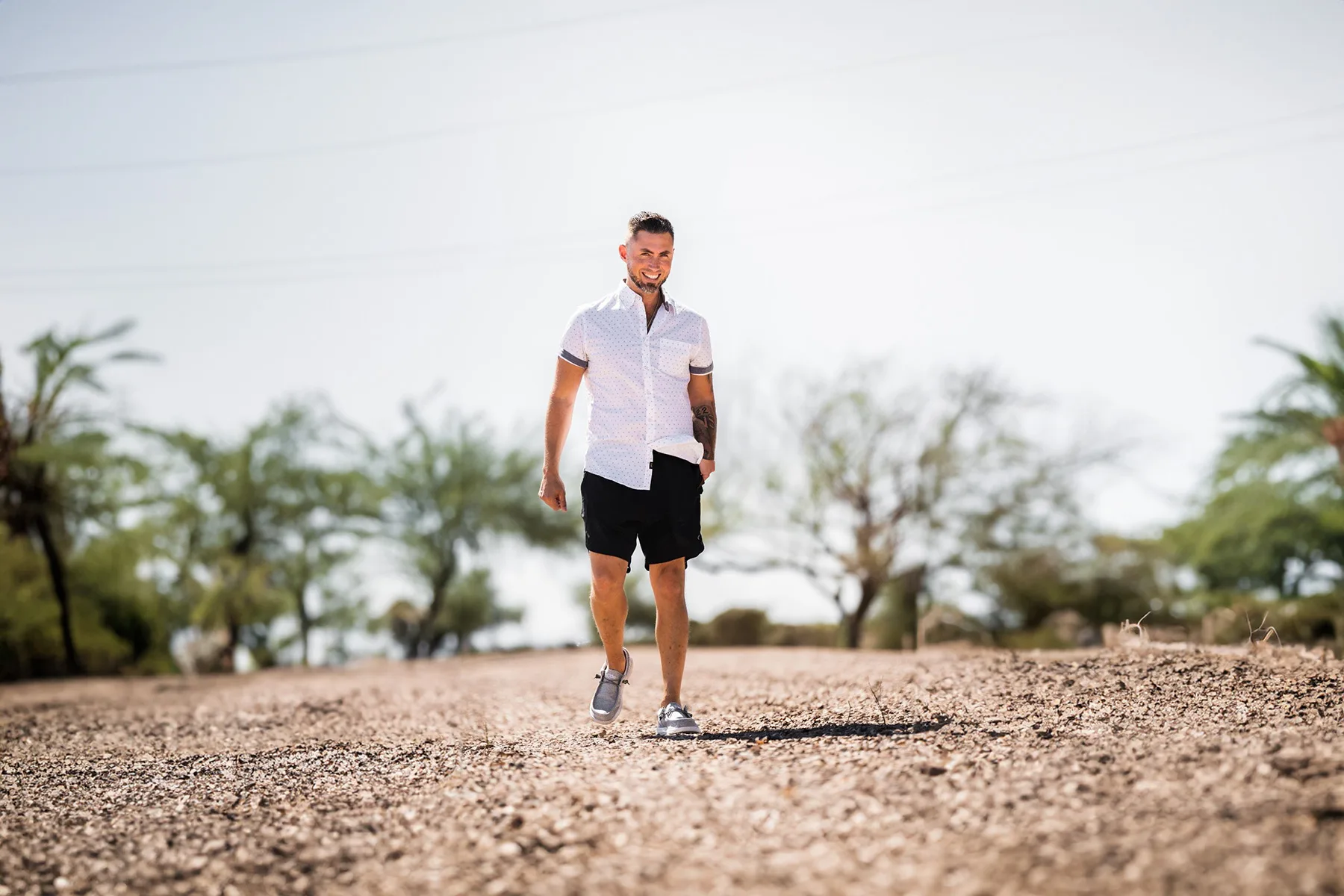 Brian Ballah walking outdoors on a sunlit path.